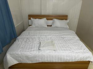 西哈努克Everest Restaurant and Guest House的一张配有白色床单和枕头的大床