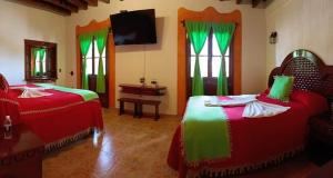 卡尔波镇Hotel El Aguila的一间卧室配有两张带绿色和红色床单的床