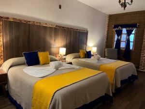 卡尔波镇Hotel El Aguila的酒店客房带两张带黄床单的床
