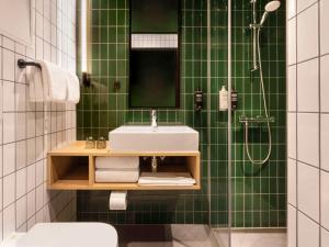 哥本哈根ibis Styles Copenhagen Orestad的绿色瓷砖浴室设有水槽和淋浴