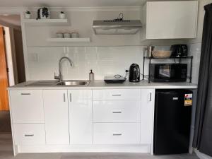 惠灵顿Hill View Abode Tawa的厨房配有白色橱柜、水槽和微波炉