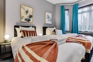 伦敦Charming Family Abode: Beautiful Home with Outdoor Space的卧室内的两张床,配有蓝色窗帘
