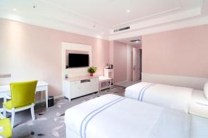 华阴华山欣源国际酒店的一间卧室配有两张床、一张桌子和一台电视。