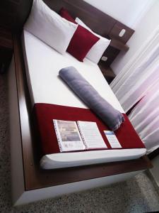 里奥内格罗Hotel Bicentenario Rionegro的一张带枕头的床和一本书