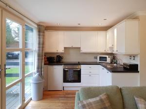 巴洛赫Leven Lodge 3 - Uk46045的厨房配有白色橱柜和沙发。