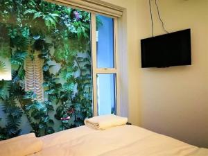 吉隆坡Swing & Pillows - KL Cheras Maluri的一间卧室,设有窗户和植物墙