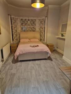 利物浦ArklesFCLiverpool的一间卧室配有一张带粉红色床单和木地板的床。