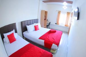 Luengbatagrand koetaradja permai hotel的一间卧室配有两张红色和白色床单
