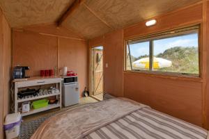 AwanuiKaro Hut B - Ninety Mile Beachfront Cabin的小房间设有床和窗户