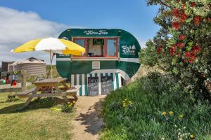 AwanuiKaro Hut B - Ninety Mile Beachfront Cabin的一张野餐桌和一辆拖车旁边的雨伞