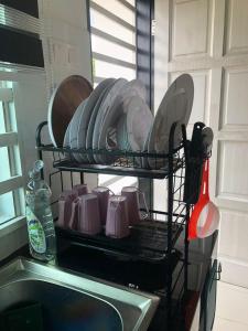 哥打巴鲁ZDH Homestay的碗架,上面装有盘子和盘子,放在水槽上