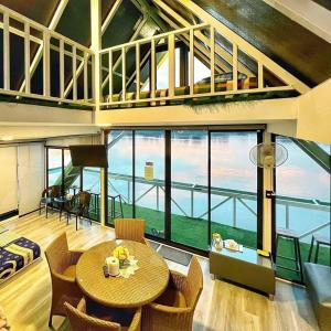 แพรุ่งธารา ไชโย (Rungtara Houseboats)的客房设有桌椅和大窗户。