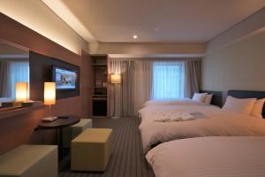 大阪Prince Smart Inn Osaka Yodoyabashi的酒店客房设有两张床和电视。