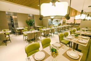 马尼拉Ardenhills Suites的餐厅设有白色的桌子和绿色的椅子
