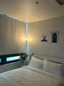 首尔If House Hongdae的卧室配有白色的床和灯