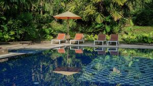 奥南海滩滨海快速酒店 - 渔人奥南的游泳池旁的两把椅子和一把遮阳伞