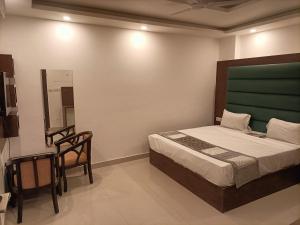 新德里Hotel Ambience Palace Near IGI Airport Delhi的一间卧室配有一张床、一把椅子和镜子