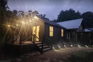 戴尔斯福特Daylesford - Frog Hollow Estate -THE COTTAGE - enjoy a relaxing and romantic night away in our gorgeous little one Bedroom ROMANTIC COTTAGE under the apple tree with water views的小屋的一侧设有灯