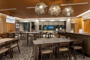 梅普尔格罗夫SpringHill Suites Minneapolis Maple Grove/Arbor Lakes的一间带桌椅的餐厅和一间酒吧