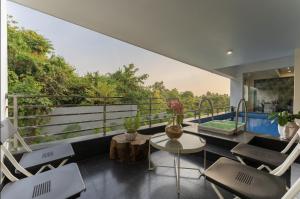 莫尔穆冈Lavish Apartments with Swimming Pool near Candolim Beach的客房设有带椅子和桌子的阳台。