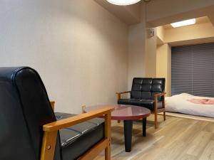热海素泊まり宿　瑞宝荘的一间设有椅子和桌子及床的等候室