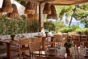 尼亚·蒙达尼亚伊卡斯大洋洲度假村的餐厅设有木桌和椅子,并种植了植物