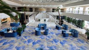 乌鲁木齐乌鲁木齐华凌雅高美爵大饭店的一个带蓝色椅子和楼梯的大型大堂