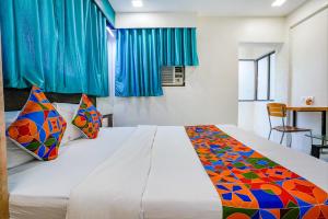 孟买FabExpress Bindra Elite的卧室配有一张带彩色枕头的大型白色床。