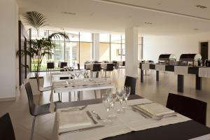 Gricignano dʼAversaInn Naples Airport的用餐室配有白色桌椅和玻璃杯