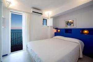 吉廖港Hotel Saraceno的卧室设有白色的床和大窗户
