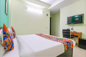 诺伊达Aruba Suites的卧室配有白色的床和电视