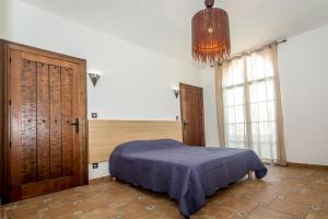 比亚里茨Résidence Prestige Odalys Les Villas Milady的一间卧室配有一张床和一个吊灯