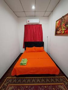 大港Fausal Legacy Homestay Sungai Besar的一间卧室配有橙色床和红色窗帘
