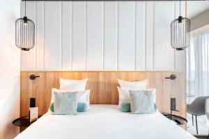 利莫内GOLDEN TULIP LYON OUEST TECHLID Hotel & Spa的一间卧室配有带白色床单和蓝色枕头的床。