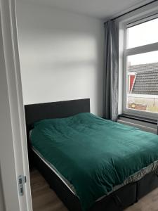 莱顿Da Costa 12A的一间卧室设有一张绿色的床和一个窗户。