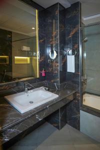 迪拜Concorde Creek View Hotel Bur Dubai的一间带水槽和玻璃淋浴的浴室