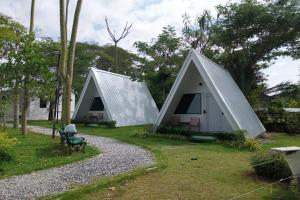 Ban Tha SaiIt my life cafe x camp的两顶白色小帐篷,草地上设有长凳