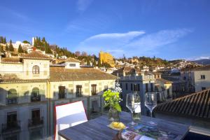 格拉纳达Casual Ilbira Granada的阳台上的桌子上摆放着酒杯