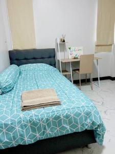 帕府Chaya Home&Hug Phrae的一张带蓝色棉被和一张桌子的床