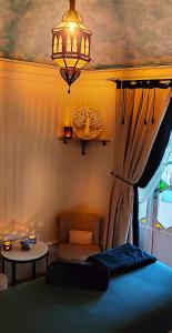萨兰莱班L'Aristoloche的一间卧室配有一张床、一个吊灯和一张桌子