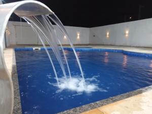 卡诺格布拉达Casa com Piscina, hidromassagem e churrasqueira.的游泳池的喷泉