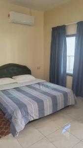 KeningauThe Backyard Cottage 168的一间卧室配有一张带蓝色窗帘的床和一扇窗户