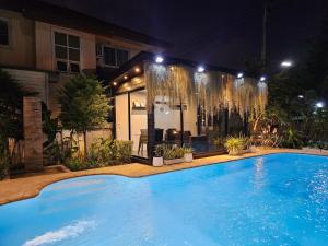 合艾My Home Pool Villa Hatyai的一座大型游泳池,在晚上在房子前面