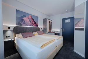 格林德尔瓦尔德Hotel Central Wolter - Grindelwald的卧室配有一张白色大床,墙上挂着群山