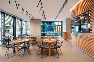 悉尼悉尼中央公园福朋喜来登酒店的餐厅设有木桌、椅子和窗户。