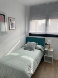 略夫雷加特河畔圣费柳Estrénalo a minutos de BCN的一间卧室配有一张带蓝色床头板的床和窗户