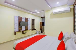 巴罗达OYO Hotel Golden的一间卧室配有一张带红色枕头的床和一台电视。