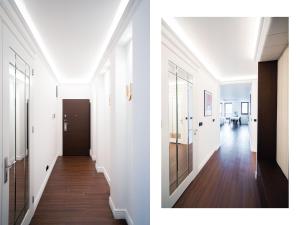 格但斯克Suite Sixteen Szafarnia的一条带白色墙壁和门的走廊,以及一条铺有木地板的走廊