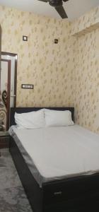 kolkataHOTEL BLUE MOON的卧室内的一张床铺,配有白色床单和墙壁