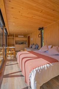 普耶韦Outscape Puyehue的木制客房内的一间卧室配有两张床